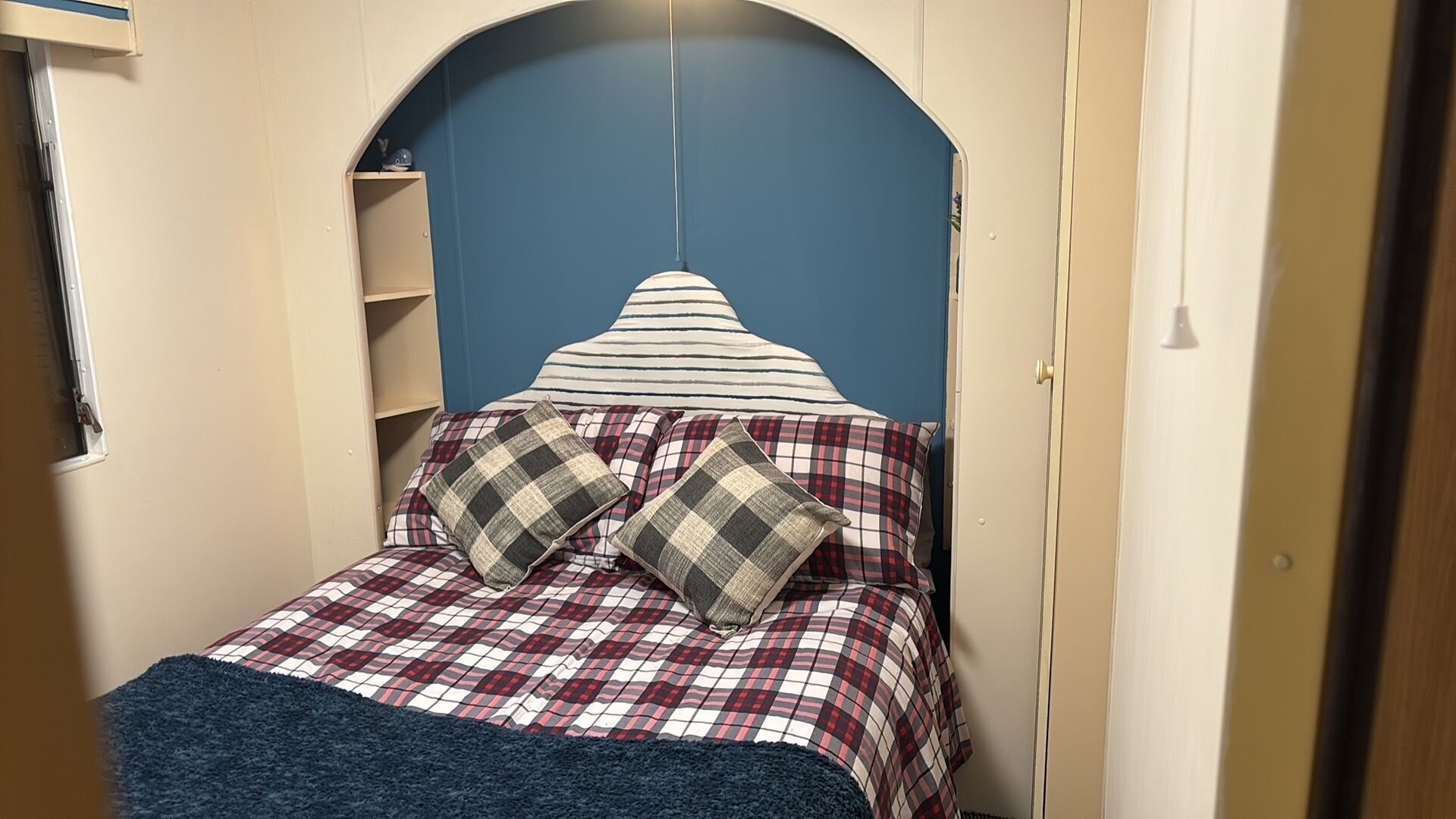 Ein Schlafzimmer mit einem Bett, einem blauen Kopfteil und einer karierten Bettdecke.