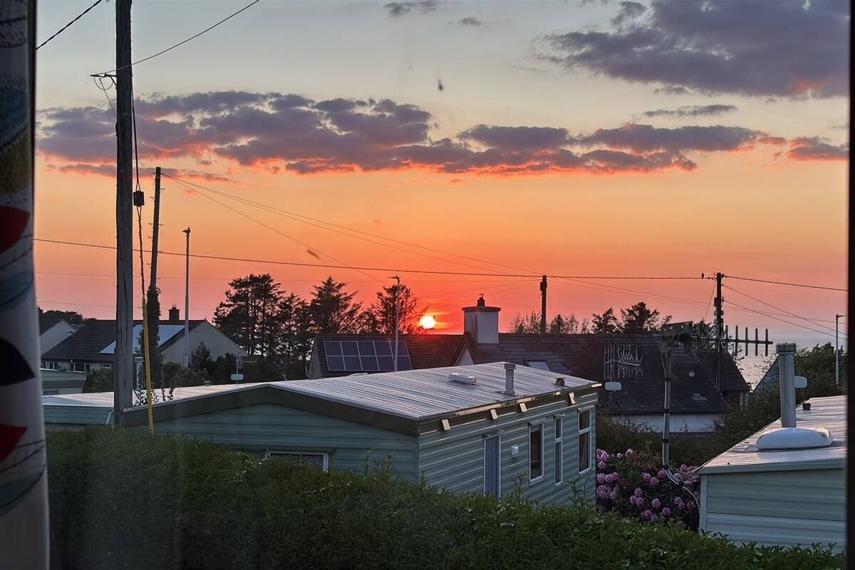 A residential area with houses, power lines, and a sunset.