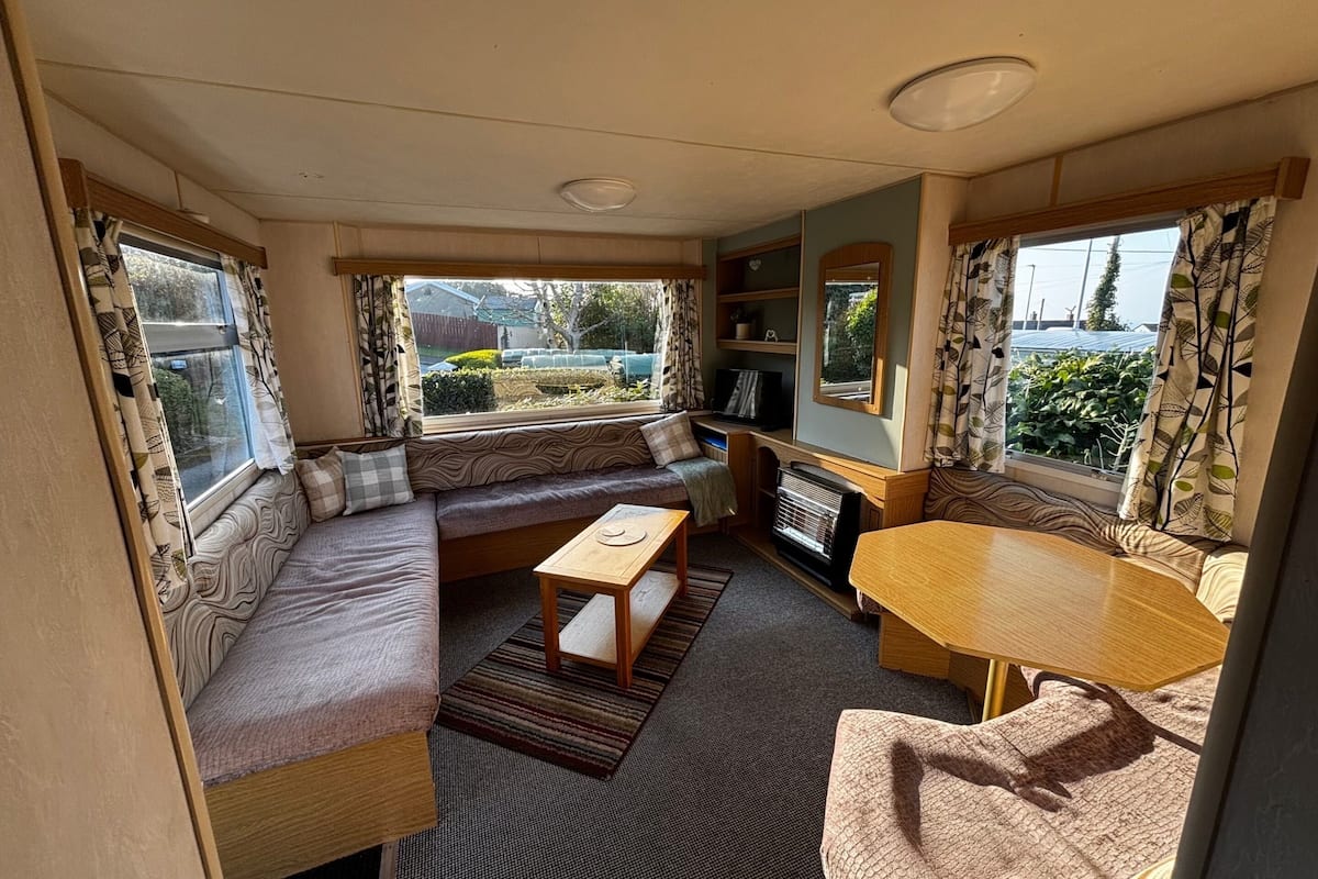 A cozy RV interior with a sofa, a small table, and a TV area.