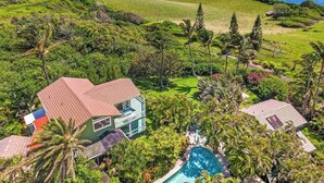 Une maison avec une piscine, entourée d’une végétation luxuriante et offrant une vue sur l’océan.