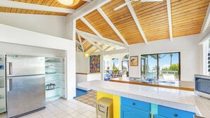 Une cuisine moderne dotée d’un grand îlot central, d’appareils électroménagers intégrés et donnant sur un balcon.