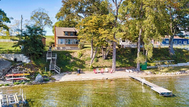 Una propiedad junto al lago con un muelle de madera, una escalera de piedra que lleva a una casa y una vista despejada del agua.