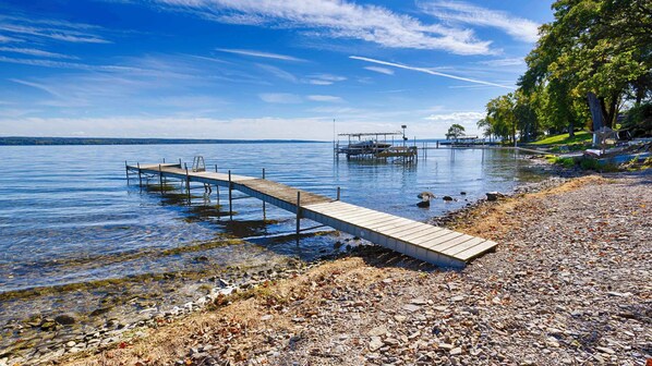 A wooden pier extending into calm waters, surrounded by a rocky shoreline and a clear sky.