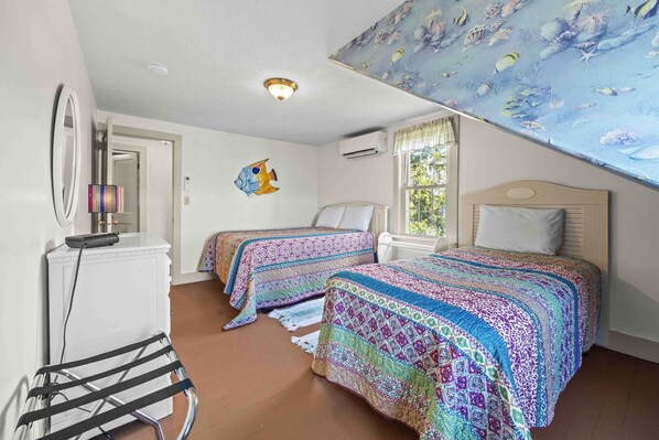 Quarto com duas camas, ventilador de teto, ar condicionado na parede e janela com cortinas.