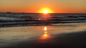 Un coucher de soleil sur l’océan, avec un navire à l’horizon.