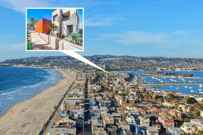 Un paisaje urbano costero con playa, puerto deportivo y edificios residenciales.