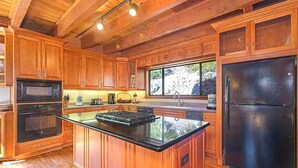Una cocina moderna con armarios de madera, un refrigerador negro y una isla grande con estufa.