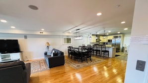 A modern living room with a flat-screen TV, a sofa, and a dining area with chairs and a table. - BIG HOUSE WITH POOL OCEANVIEW 3 DECKS, 3 MASTER VERY NEAR OCEAN AND BOSRDWALK (Wildwood Crest)