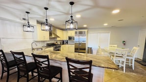 A modern kitchen with a central island, dark wooden chairs, and stainless steel appliances. - BIG HOUSE WITH POOL OCEANVIEW 3 DECKS, 3 MASTER VERY NEAR OCEAN AND BOSRDWALK (Wildwood Crest)