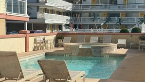 A pool area with lounge chairs and a building with balconies in the background. - BIG HOUSE WITH POOL OCEANVIEW 3 DECKS, 3 MASTER VERY NEAR OCEAN AND BOSRDWALK (Wildwood Crest)