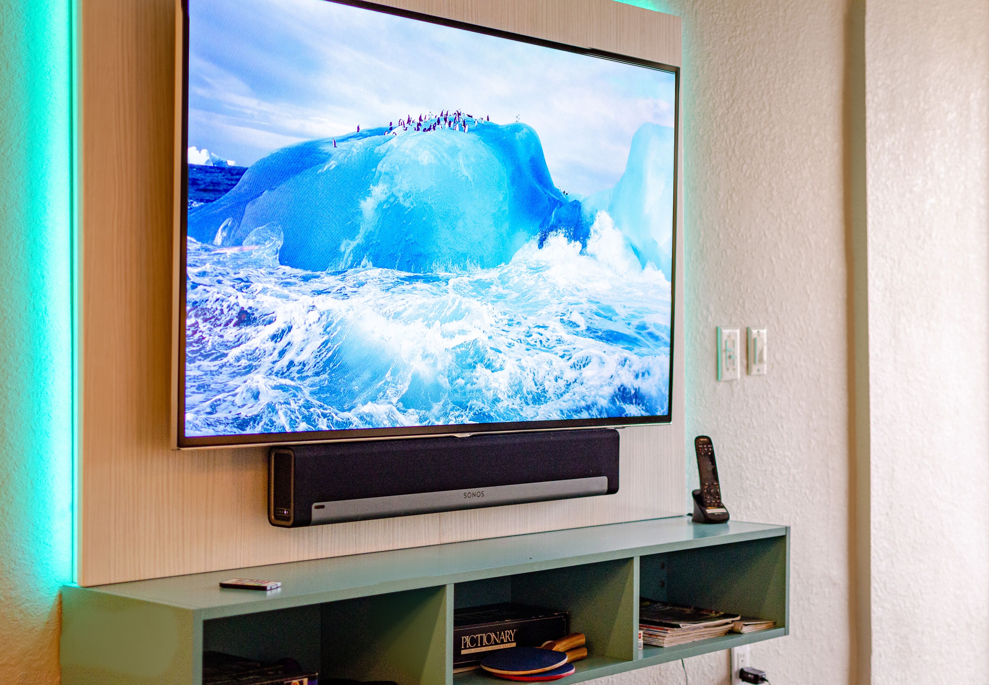 A flat-screen TV mounted on a wooden wall with a shelf below.