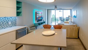 Eine moderne Küche mit Essbereich, einem an der Wand befestigten Fernseher und einem Balkon mit Sitzgelegenheit.