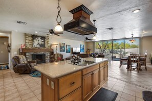 A spacious kitchen with a large island, a fireplace, and a dining area with a view. - Acre+ lot, country quiet, city close, pool can be heated, BBQ, pond, firepit. (Cave Creek)