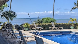 A poolside area with lounge chairs, a clear view of the ocean, and a stone deck. - MOLOKAI ISLAND   Two Bedroom Oceanfront Top End Unit!  (Kaunakakai)