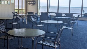 A spacious indoor area with multiple tables and chairs, large windows offering a view of the sea, and a sign reading "GENERA AVECREST STORE". - MOLOKAI ISLAND   Two Bedroom Oceanfront Top End Unit!  (Kaunakakai)