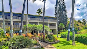 A multi-story hotel with balconies, surrounded by tropical vegetation and palm trees. - MOLOKAI ISLAND   Two Bedroom Oceanfront Top End Unit!  (Kaunakakai)