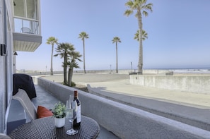 Een balkon met uitzicht op het strand, palmbomen en een tafel met wijnflessen.