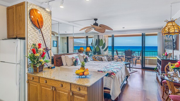 A modern kitchen with a large island, wooden cabinets, and a view of the ocean.