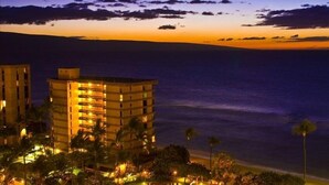 A hotel with multiple floors, a beach view, and palm trees.