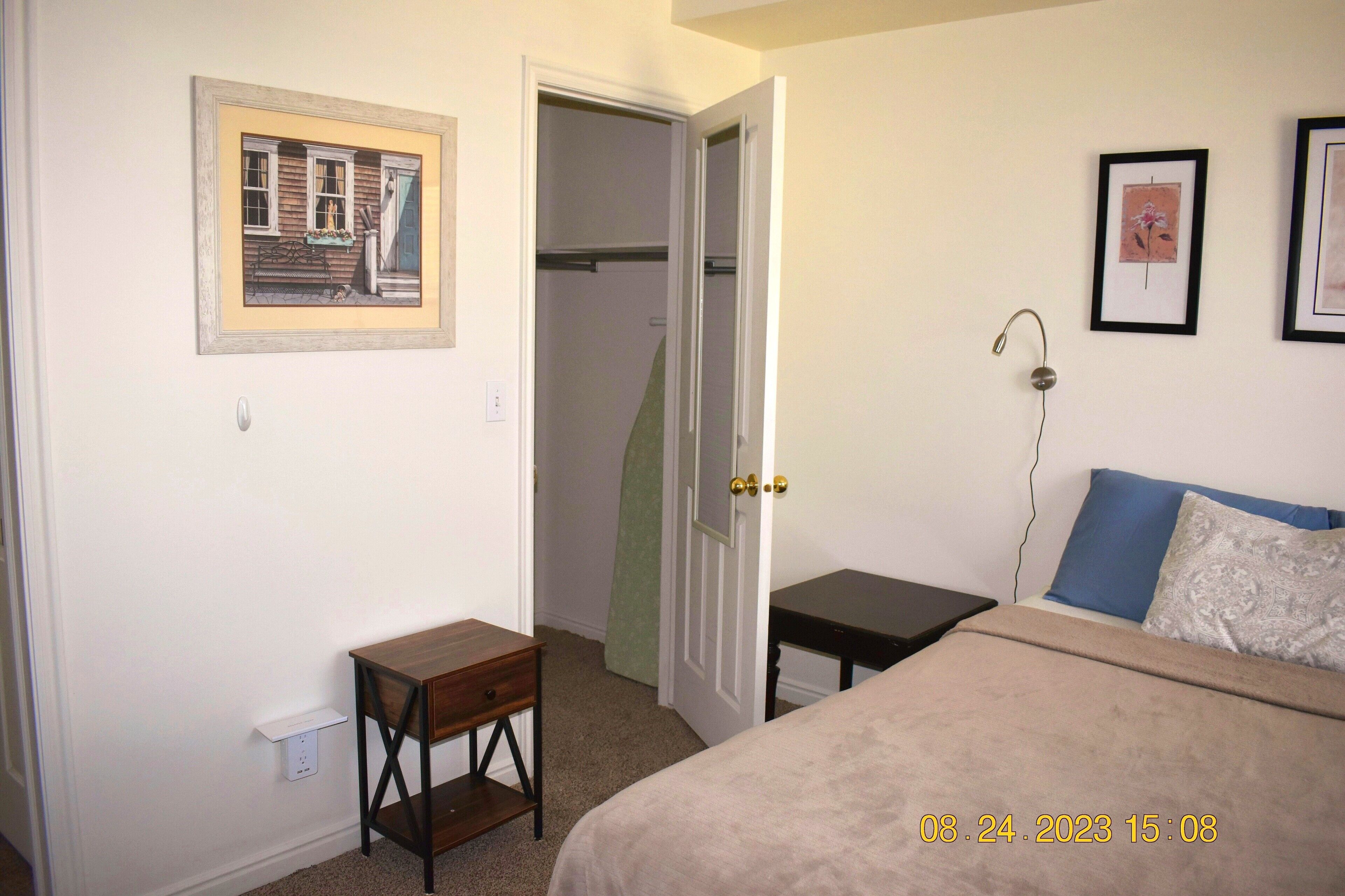 Une chambre à coucher avec un lit, une table de chevet et une commode. Une porte donne accès à un placard.