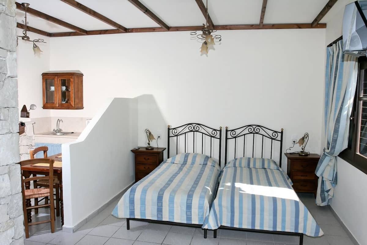 A bedroom with a bed, bedside tables, a wooden cabinet, a desk, and a chair.