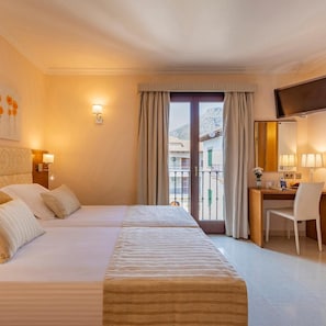 A hotel room with a bed, a desk, a chair, a television, and a window with curtains.