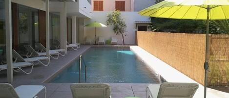 A pool area with lounge chairs and umbrellas.