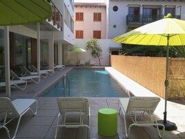 Un área de piscina con sillones de descanso y sombrillas.