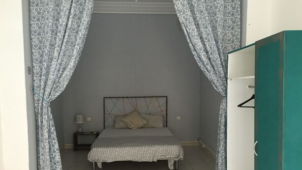 Un dormitorio con cama, cortinas, una mesita de noche y un armario.