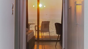 A corridor leading to a balcony with a view of the sunset over the water. - Sunrise Aparthotel Rhodes (Rhodes)