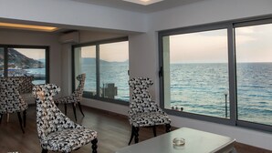 A modern room with large windows overlooking the sea, featuring patterned chairs and a table. - Sunrise Aparthotel Rhodes (Rhodes)