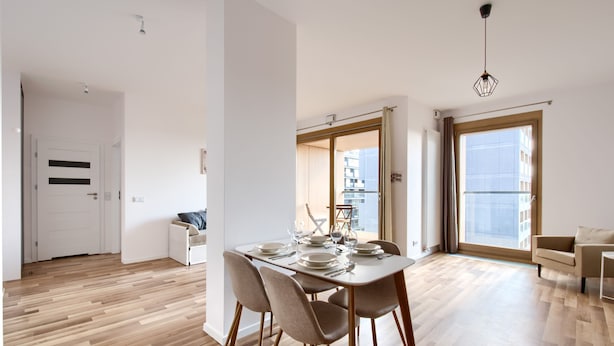 Un apartamento moderno con zona de comedor, un sofá y un amplio ventanal.