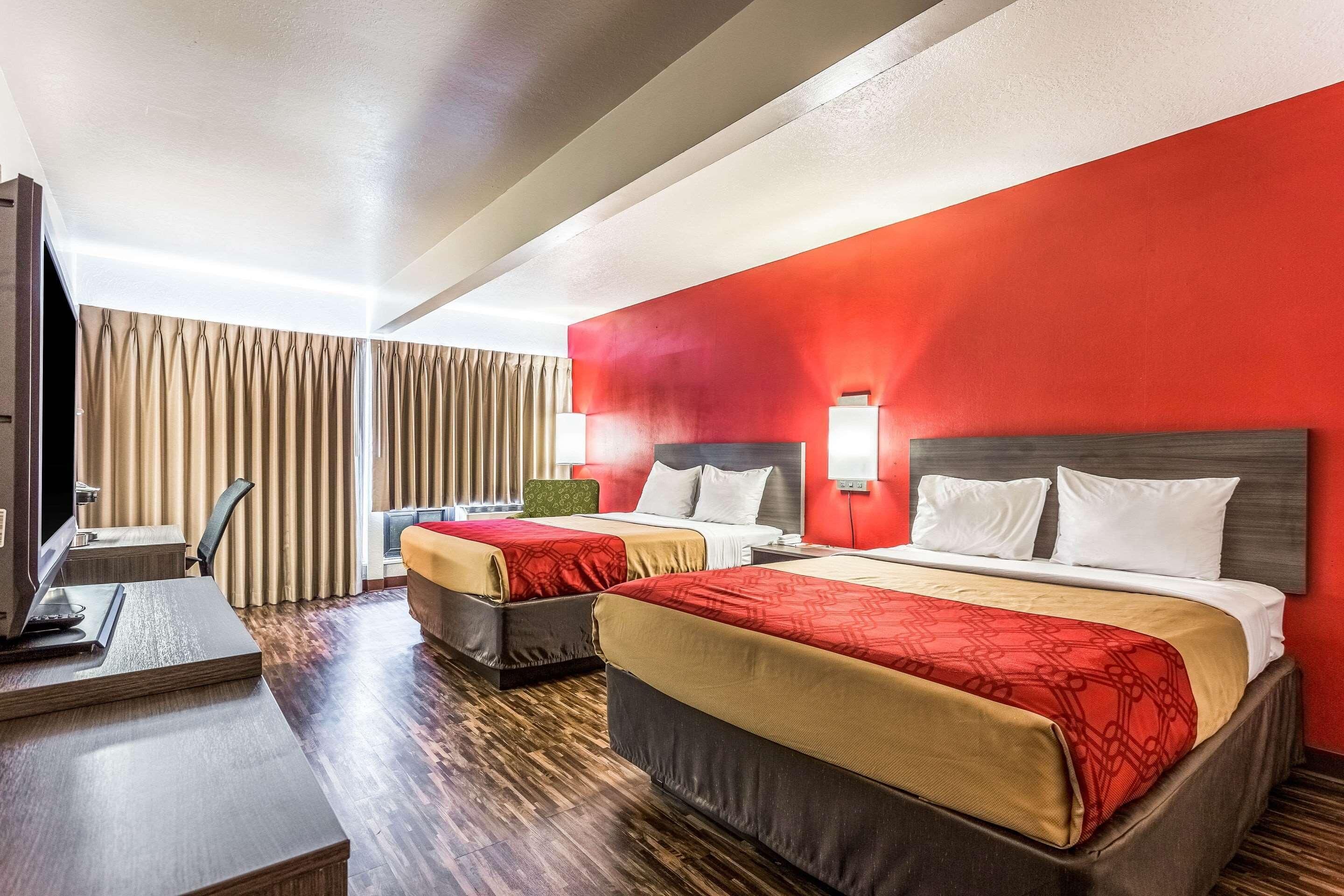 A hotel room with two beds, a desk with a computer, and a TV.