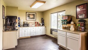 A kitchen with white cabinets, a microwave, and a coffee station with various coffee makers and containers. - Econo Lodge Idaho Falls (Idaho Falls)