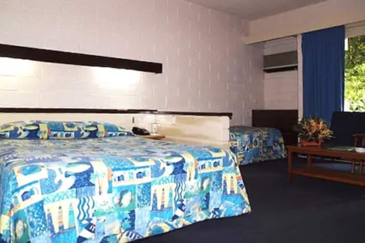 A hotel room with two beds, a desk, and a window with curtains.