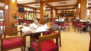 Un comedor espacioso con vigas de madera, sillas tapizadas rojas y una barra al fondo.