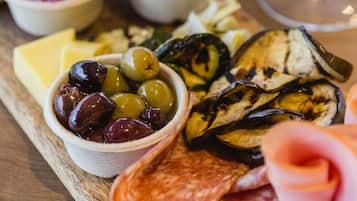A charcuterie board with various cheeses, olives, pickles, and meats.