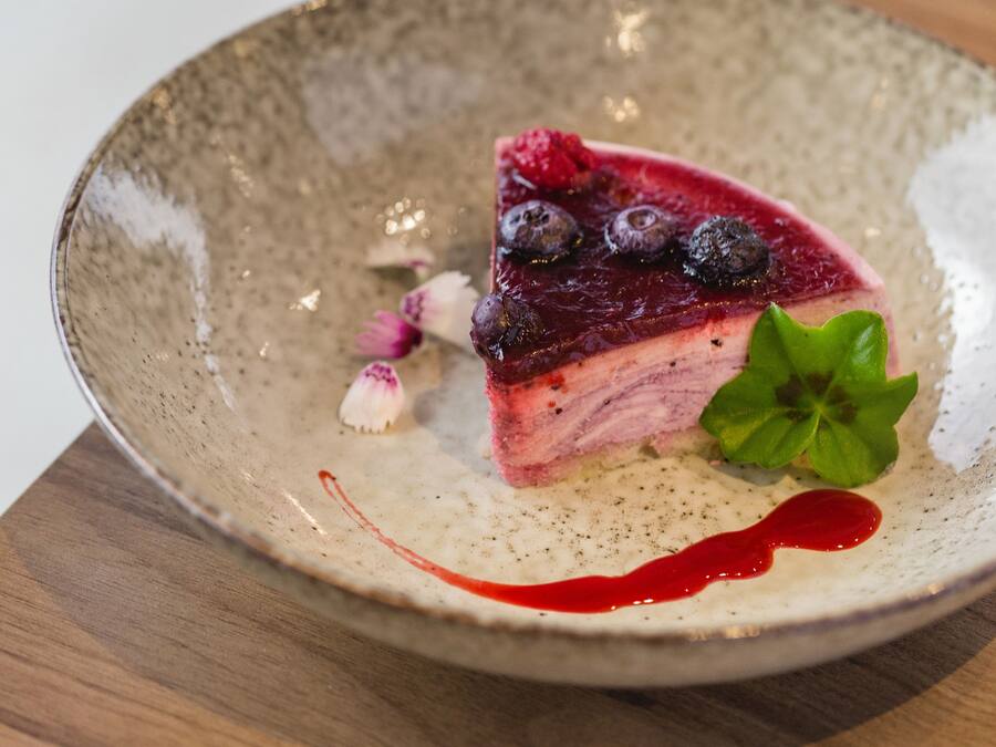 A slice of pie with berries and a mint leaf on a ceramic plate.