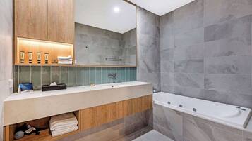 Un baño moderno con tocador de madera, un espejo grande y una bañera.
