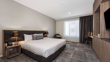 Una habitación de hotel moderna con una cama grande, un escritorio, una silla y un televisor.