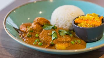 Un plato de curry, arroz y un acompañamiento.