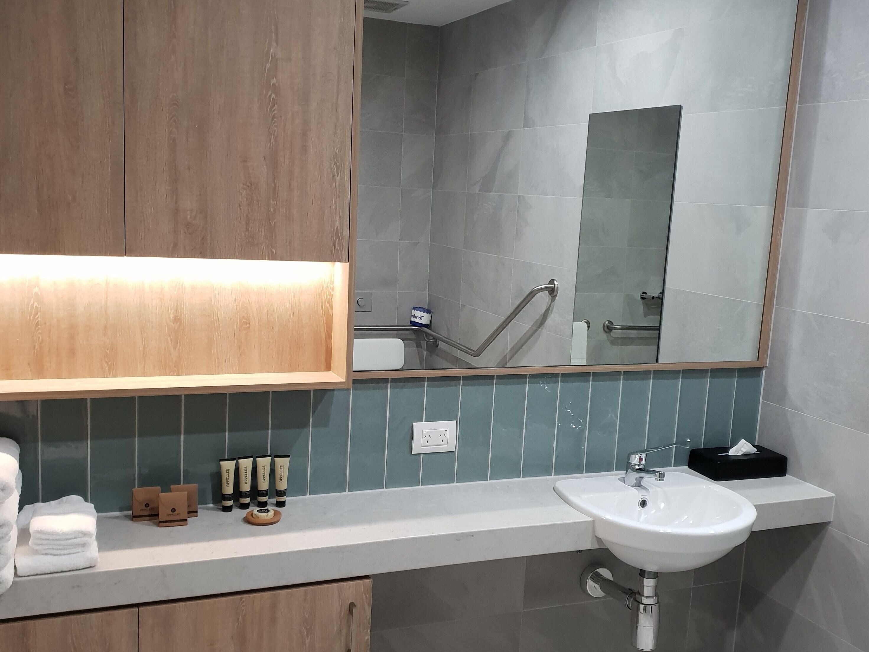 Un baño moderno con tocador de madera, un espejo grande y un lavabo blanco.