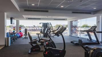 Un gimnasio con cintas de correr, elípticas y pesas sueltas.