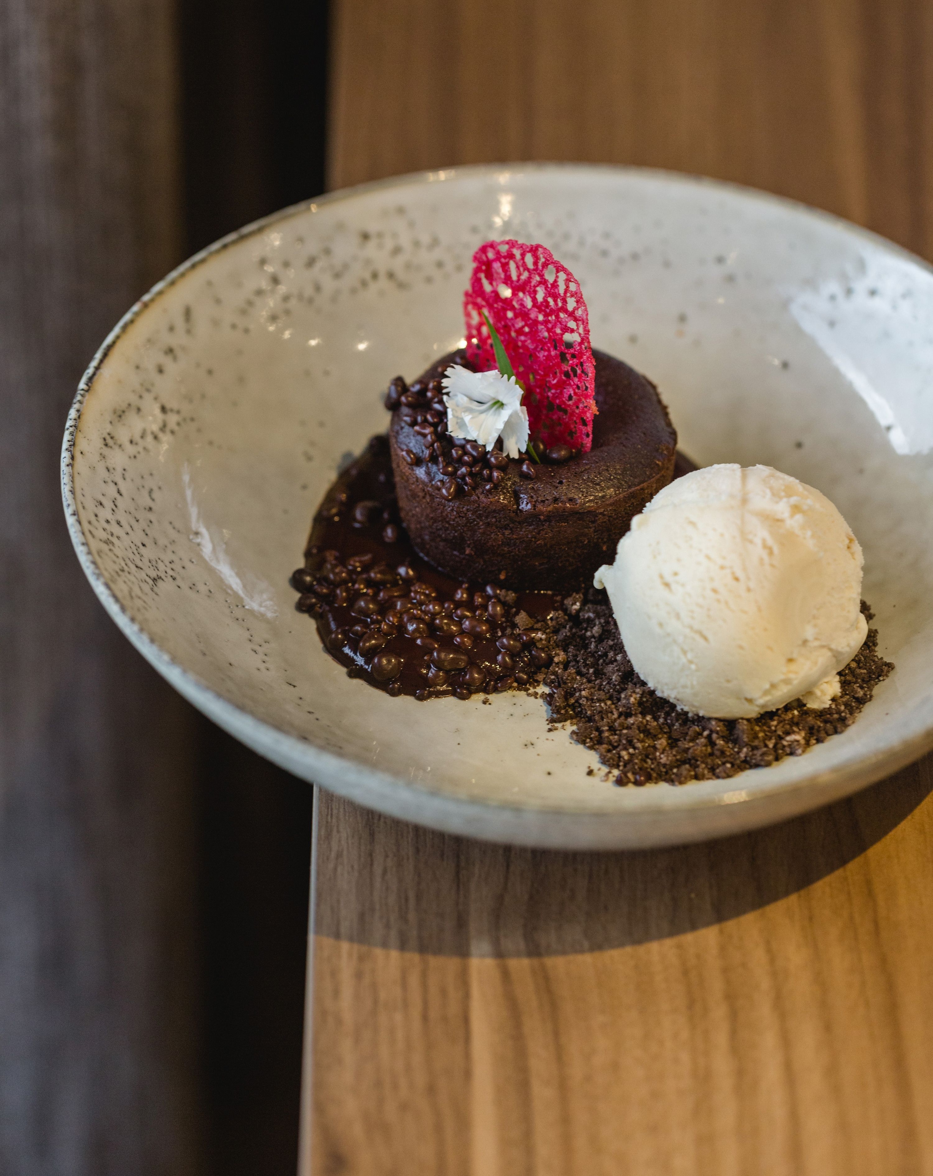 A dessert plate with a chocolate cake, a scoop of vanilla ice cream, and a strawberry on top.