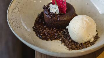 A dessert plate with a chocolate cake, a scoop of vanilla ice cream, and a strawberry on top.