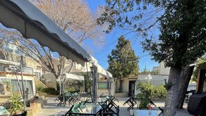 An outdoor patio area with tables and chairs, surrounded by trees and buildings. - Hotel Les Cigalons (Marseille)