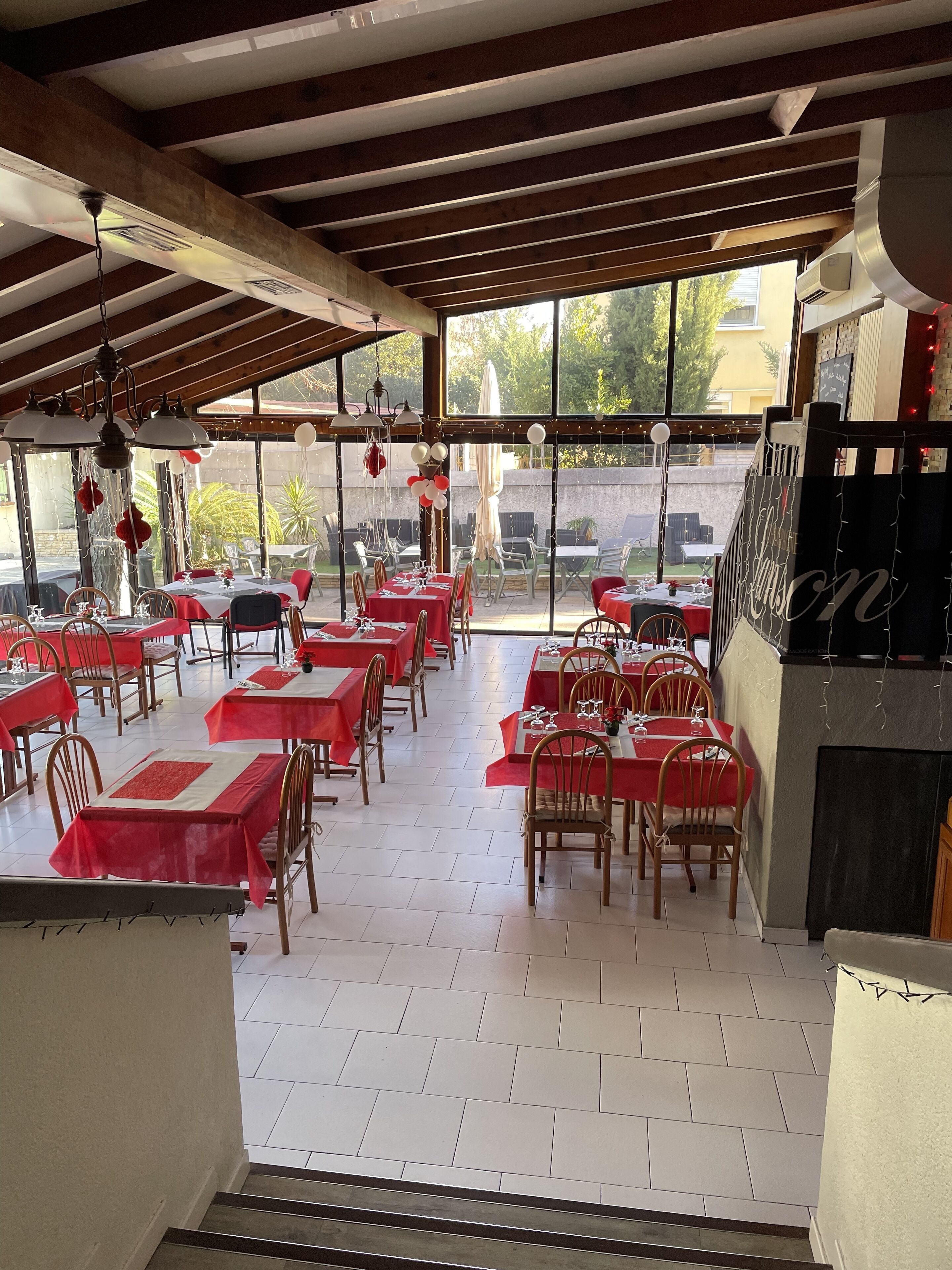 A restaurant with multiple tables set for dining, featuring a mix of indoor and outdoor seating.