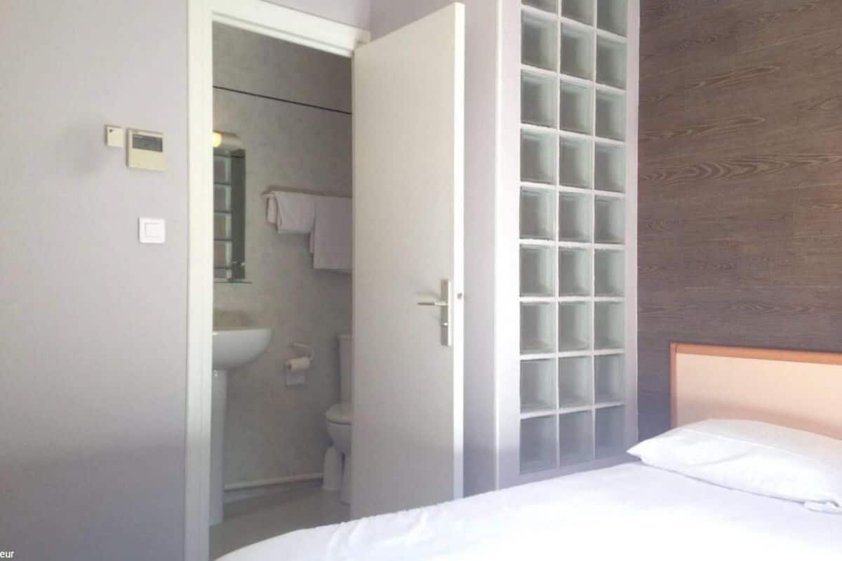 Une chambre d’hôtel avec un lit, une armoire et une salle de bain visible à travers une porte ouverte.