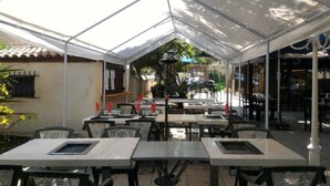 An outdoor dining area with tables and chairs under a large white canopy. - Hotel Les Cigalons (Marseille)