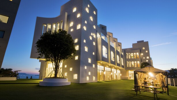 A modern building with multiple windows and a well-maintained lawn. - La Terrace Resort (Yeosu)